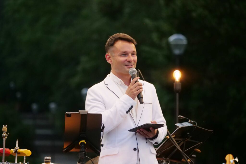 Konferansjer na scenie podczas wieczorku muzycznego z Five O'Clock Orchestra w Parku Miejskim w Wojkowicach 2 lipca 2022
