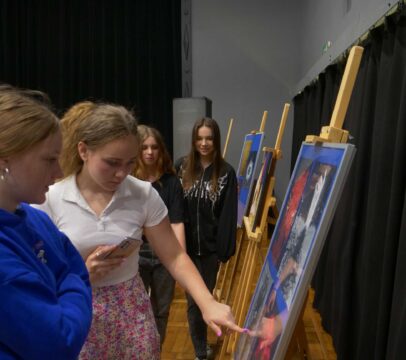uczniowie oglądający obrazy na wernisażu malarskiego "Podróże wyobraźni" uczniów ZSOiT w Wojkowicach w Miejskim Ośrodku Kultury w Wojkowicach