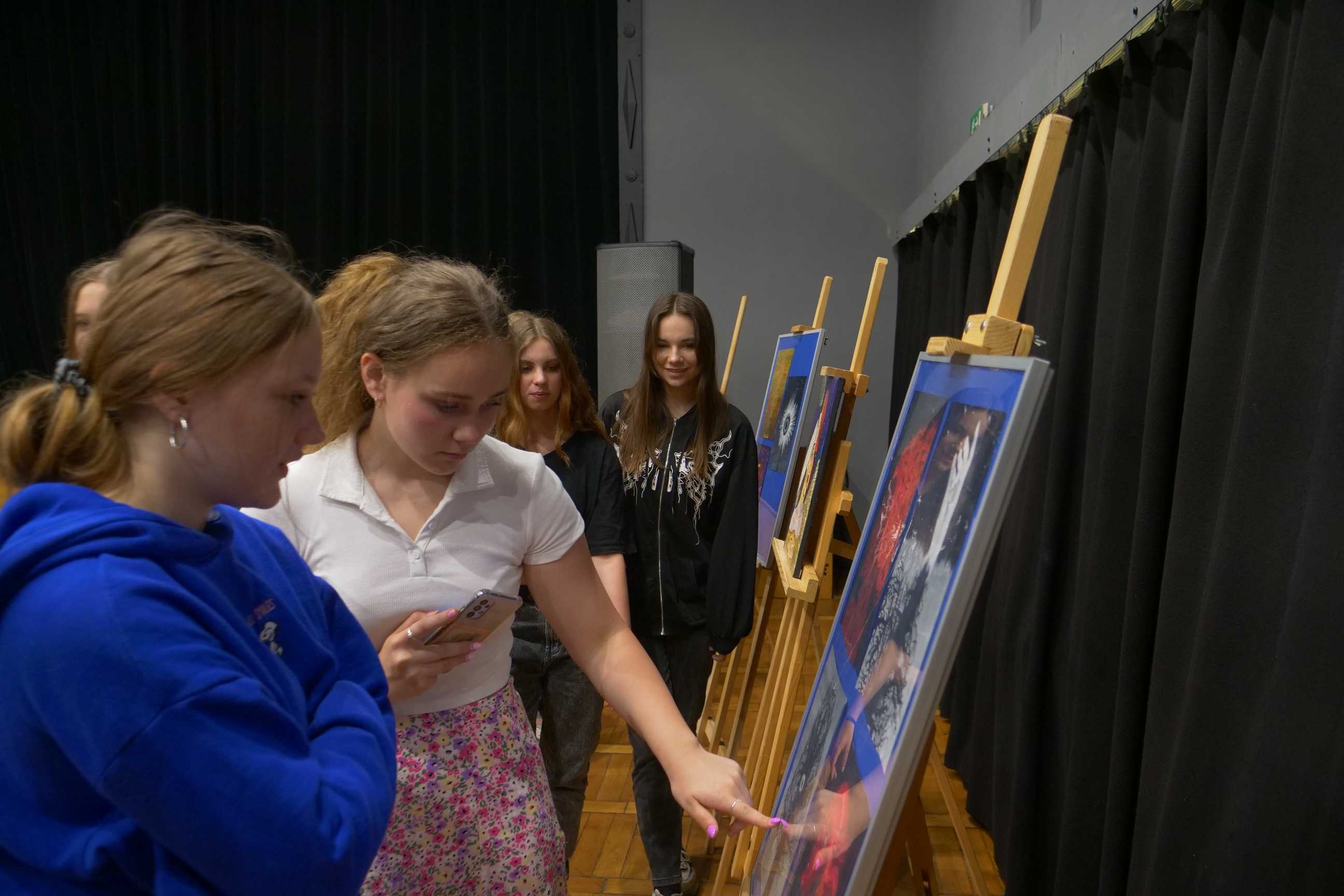 uczniowie oglądający obrazy na wernisażu malarskiego "Podróże wyobraźni" uczniów ZSOiT w Wojkowicach w Miejskim Ośrodku Kultury w Wojkowicach